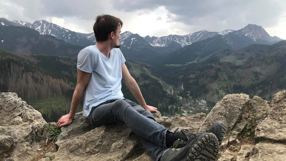 Hombre sentado en una montaña mirando al valle